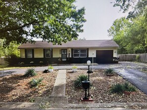 Ein eingeschossiges Haus mit Garage, Veranda und Auffahrt.