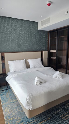 Ein Hotelzimmer mit einem großen Bett, einem Kopfteil, einem Schrank und einem gemusterten Teppich.