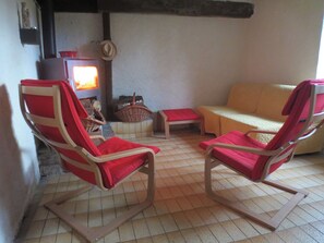 A cozy living room with two rocking chairs, a sofa, a fireplace, and a television.