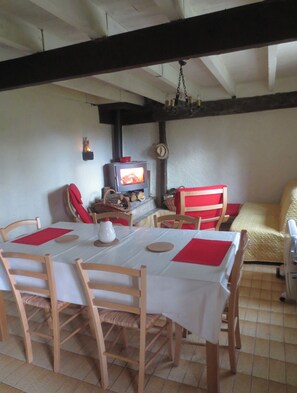 A dining area with a table set for four, wooden chairs, a television, and a fireplace.