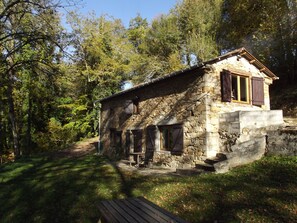 Un bĂątiment en pierre dotĂ© dâun porche en bois, entourĂ© dâarbres.