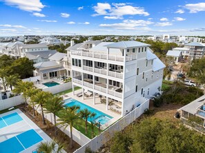 Ein mehrstöckiges Wohnhaus mit Pool, umgeben von Palmen und anderen Häusern.