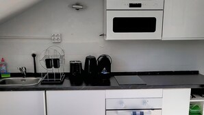 A compact kitchen with white cabinets, a built-in oven, a coffee maker, and a sink. - DG "R" Helle 40m² City Wohnung 15 min. von Salzburg (Freilassing)