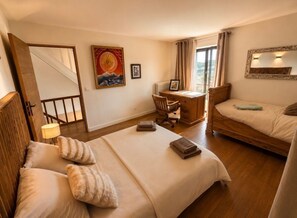 A hotel room with a bed, a desk, a chair, a lamp, a mirror, and a window. - Gite Chambord - 15 Pers. Mont-Saint-Michel Bay (Dragey-Ronthon)