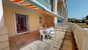 Ein Balkon mit Tisch und Stühlen, einem weißen Zaun und einem Gebäude im Hintergrund.