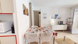 Ett kompakt bostadsutrymme med en matplats, ett litet kök och en liten TV.