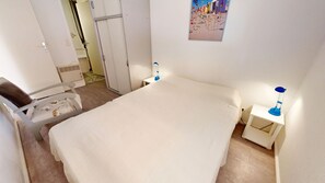 Ein Schlafzimmer mit einem Bett, einem Sessel, einem Nachttisch und einer Wandlampe.