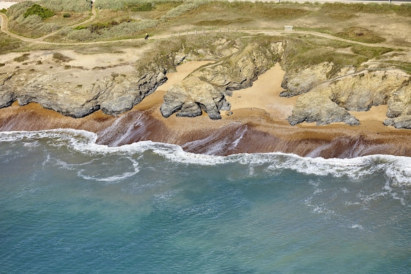 Eine Küstenlandschaft mit felsigen Klippen, einem Sandstrand und freiem Blick auf den Ozean.