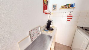 Eine kleine Küche mit Wasserkocher, Kaffeemaschine und einem Regal mit Gewürzen.