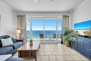 Ein Wohnzimmer mit Sofa, Couchtisch, Fernseher und einem Balkon mit Meerblick.