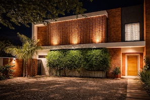 A modern two-story building with a brick facade, a green climbing wall, and a well-lit entrance. - 6 Guest House Spacious: Quincho Swimming Pool Games (San Bernardino)