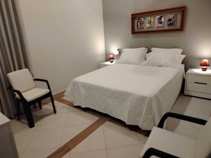 A bedroom with a bed, two bedside tables with lamps, a chair, and a framed picture on the wall. - 6 Guest House Spacious: Quincho Swimming Pool Games (San Bernardino)