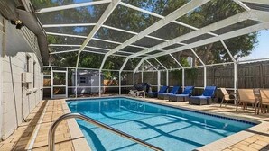 Una piscina techada con estructura metálica, sillas de descanso y un muelle de madera.