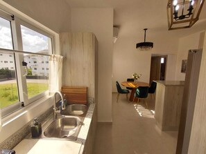 A modern kitchen with a window, a dining area with a table and chairs, and a chandelier. - 2 Bedroom Elegant Penthouse 400m from Punta Popy Beach in Las Terrenas (Las Terrenas)
