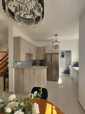 A modern kitchen with wooden cabinets, a central island, and a stainless steel refrigerator. - 2 Bedroom Elegant Penthouse 400m from Punta Popy Beach in Las Terrenas (Las Terrenas)