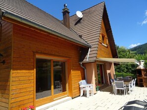 Eine Holzhütte mit Terrasse, Schiebetüren und Sitzgelegenheiten im Freien.