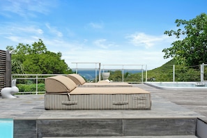 A modern outdoor seating area with a pool, overlooking a scenic landscape. - Villa Anse Marcel piscine & jacuzzi (Anse Marcel)
