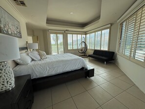 A bedroom with a bed, a chair, a sofa, a lamp, and a painting. - Aguacaliente Grand Residence- Jacuzzi, Games & Fun (Tijuana)