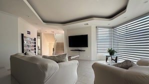 Een moderne woonkamer met een zithoek, een flatscreen televisie en een trap naar een hoger niveau.