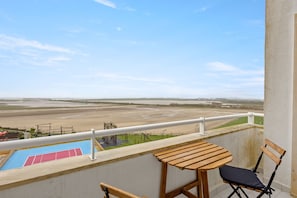 Ein Balkon mit Blick auf einen Sportplatz und eine Sandfläche.