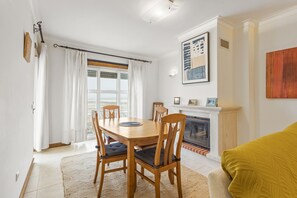 Ein Essbereich mit Tisch, Stühlen, einem Kamin und Blick durch das Fenster.
