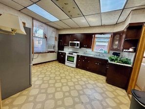Una cocina equipada con refrigerador, estufa, microondas y pileta.