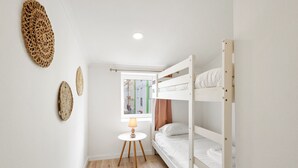 Dormitorio con literas, una mesita, una lámpara, una ventana con vistas a edificios y decoración en las paredes.