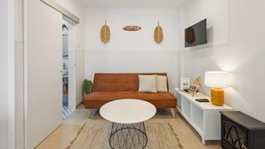 Una sala de estar moderna con un sofá marrón, una mesa blanca y un televisor montado en la pared.