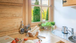 A kitchen with wooden cabinetry, a window with a view of trees, a sink, and various kitchen items. - Half of a Semi-detached House With a Sauna (Koscielisko)