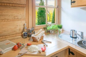 A kitchen with wooden cabinetry, a window with a view of trees, a sink, and various kitchen items. - Half of a Semi-detached House With a Sauna (Koscielisko)