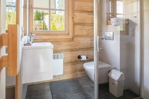 A modern bathroom with a wooden accent wall, a white sink, a toilet, and a trash bin. - Half of a Semi-detached House With a Sauna (Koscielisko)