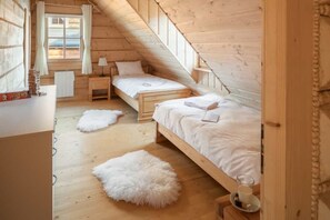 A cozy attic bedroom with wooden walls, two beds, a window with curtains, a bedside table, and a fluffy rug. - Half of a Semi-detached House With a Sauna (Koscielisko)
