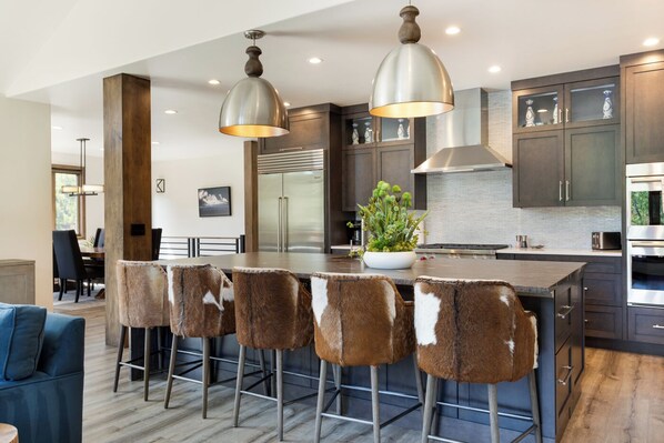 A modern kitchen with a central island, bar stools, stainless steel appliances, and pendant lighting. - Glacier Court 1854 A | 4BR Vail, Hot Tub, AC, Mtn Views (Vail)