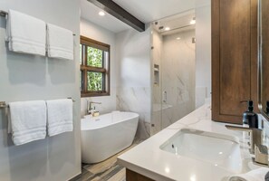 A modern bathroom with a freestanding bathtub, a glass-enclosed shower, and a large mirror. - Glacier Court 1854 A | 4BR Vail, Hot Tub, AC, Mtn Views (Vail)