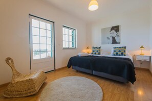 Un dormitorio con una cama, una silla, un tapete redondo y dos ventanas.