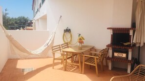 A patio with a hammock, wooden table and chairs, a grill, and a hose. - Apartment 'Refugio Da Longueira' with Private Terrace, Balcony and Wi-Fi (Nascedios)