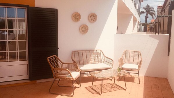 A patio with wicker furniture, a glass table, and decorative wall art. - Apartment 'Refugio Da Longueira' with Private Terrace, Balcony and Wi-Fi (Nascedios)