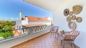 A balcony with a view of buildings and a tower, wicker chairs, and decorative wall art.
