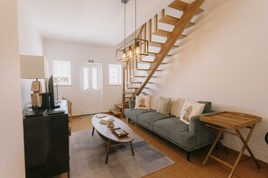Ein Wohnzimmer mit Sofa, Couchtisch, TV-Schrank und einer Holztreppe.