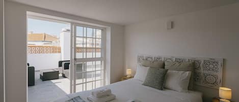 Una camera d'albergo con un letto, due comodini, una finestra e vista sull'esterno.