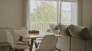 Ein Essbereich mit Tisch, Stühlen, einer Couch und Blick durch ein Fenster.