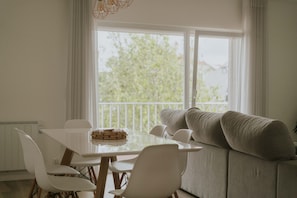 Ein Essbereich mit Tisch, Stühlen, einer Couch und Blick durch ein Fenster.
