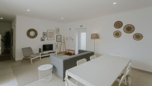 Ein modernes Wohnzimmer mit einer Couch, einem Fernseher und einem Esstisch.