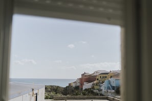 Eine Küstenstadt mit bunten Häusern, Blick auf das Meer und einer Steinmauer.