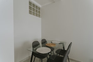 A glass-top dining table with four chairs, a woven placemat, and a small window with a grid pattern. - Best Houses 96 - Lobo do Mar (Peniche)