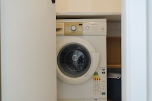A front-loading washing machine with a control panel, a detergent dispenser, and a label indicating it is a front-loading model. - Best Houses 96 - Lobo do Mar (Peniche)