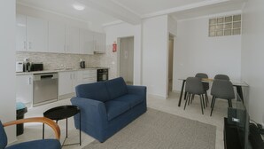 Un salon moderne avec un canapé bleu, une petite table et un téléviseur.