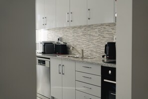 A modern kitchen with white cabinets, a microwave, a coffee maker, and a dishwasher. - Best Houses 96 - Lobo do Mar (Peniche)