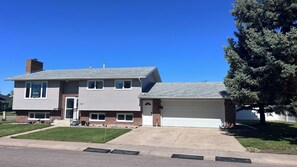 A two-story house with a garage, a front lawn, and a large tree.