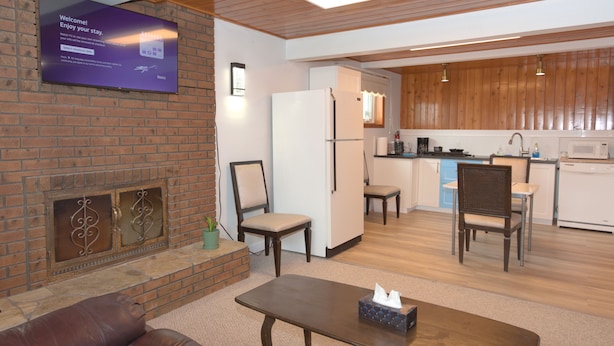 Un espacio moderno con zona de estar, chimenea, televisor de pantalla plana, cocina con armarios de madera y comedor.